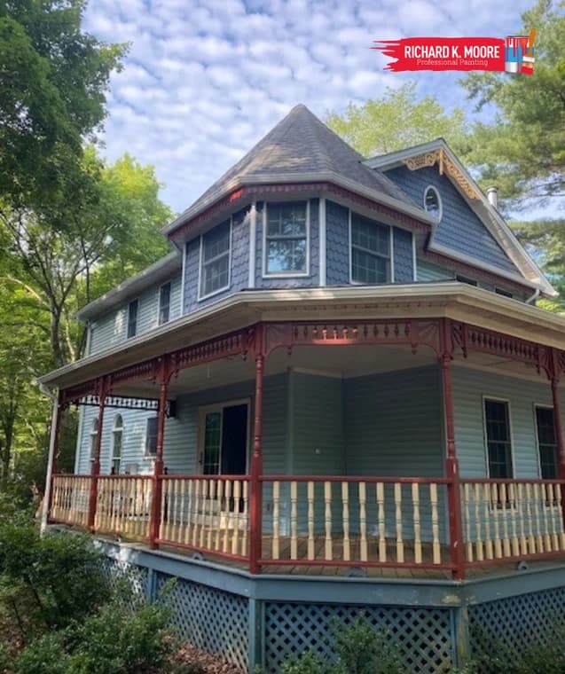 This is an image from Richard K. Moore Professional Painting in New Jersey. It shows a Victorian-style home with detailed trim painted in soft blue and red accents.