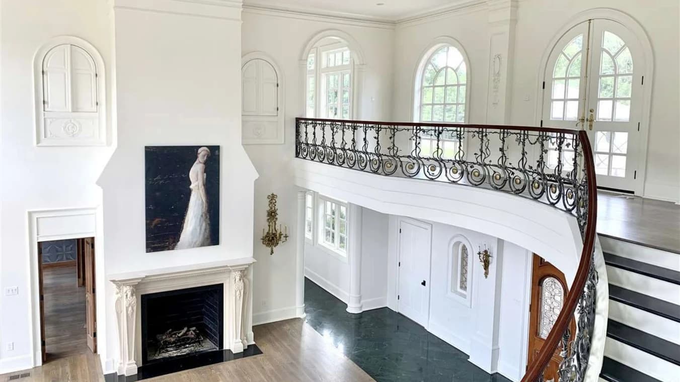Interior painting by Caldwell Painting Memphis in Cordova, Tennessee. The image shows white walls, arched windows, a fireplace, and an ornate staircase.
