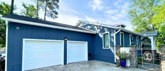 This is an image from 360 Painting of Wichita. The image shows a blue house exterior with white trim and two white garage doors.