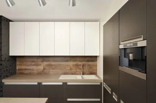 This is an image from The Woodlands Paint Doctor, located in Texas. The kitchen scene shows modern cabinetry with white upper cabinets, dark lower cabinets, and wood-style backsplash.