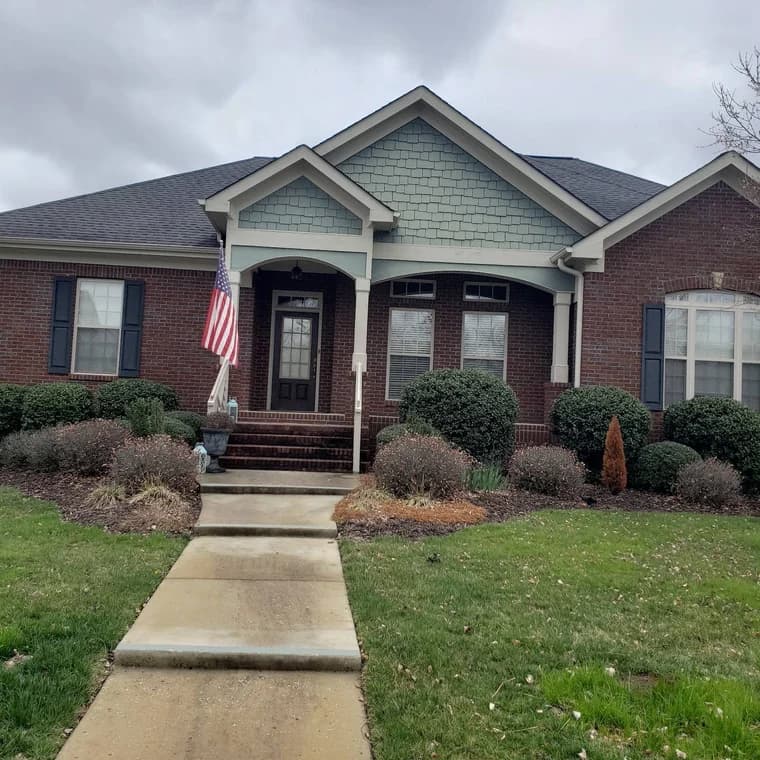 Four Bridges Painting painting project in Chattanooga, Tennessee. The image shows a brick home entry with light siding and dark shutters.