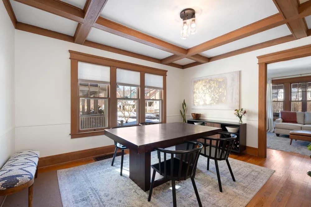 This is an image from Empire Painting Services LLC, located in New Jersey. The image shows a professionally painted dining room interior with white walls, warm wood trim, coffered ceiling details, and hardwood flooring.