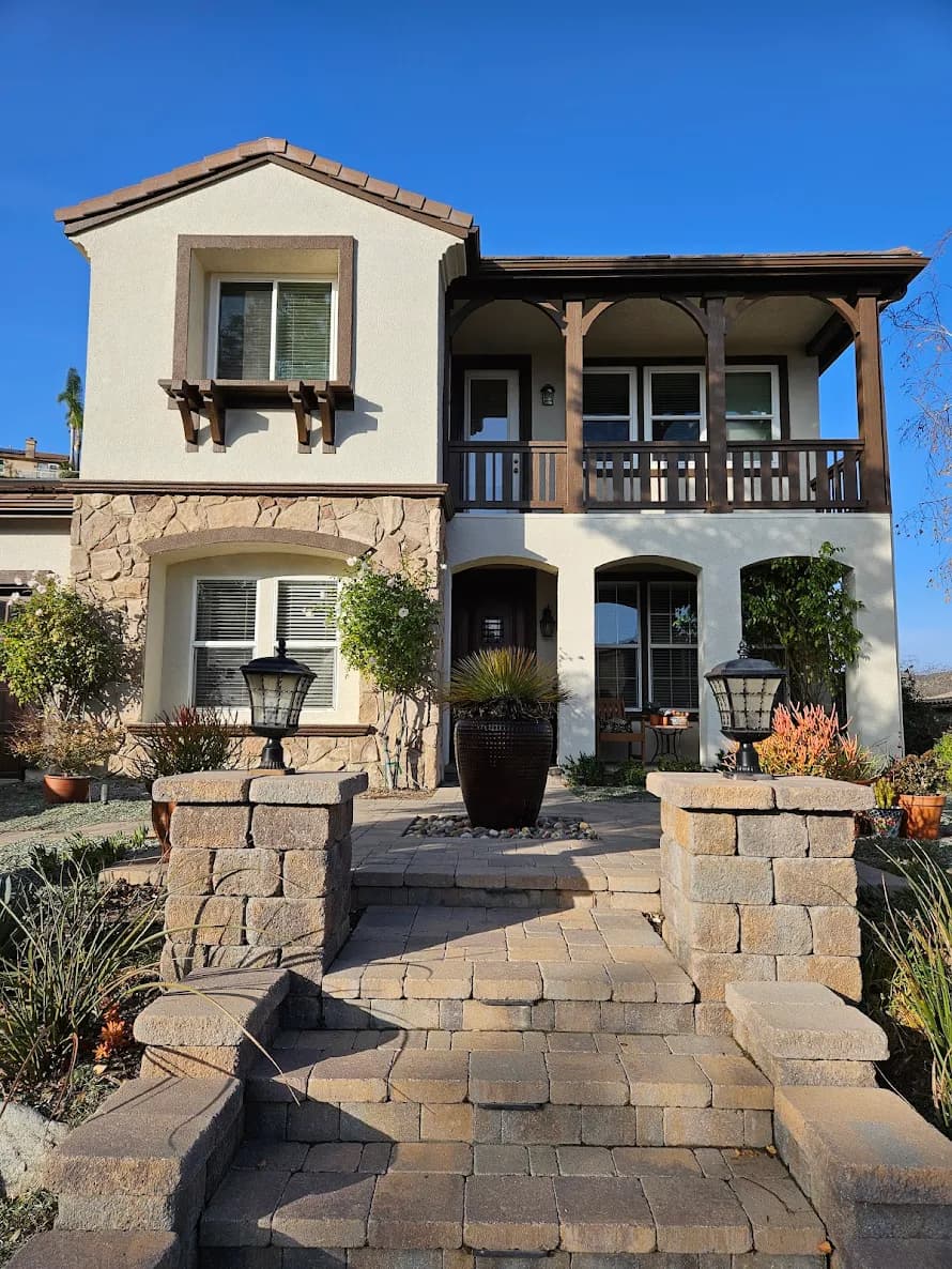 This is an image from ALLBRiGHT Painting, located in California. The image is from ALLBRiGHT Painting and shows exterior painting on a stucco and stone home with a wooden balcony and landscaped entry.