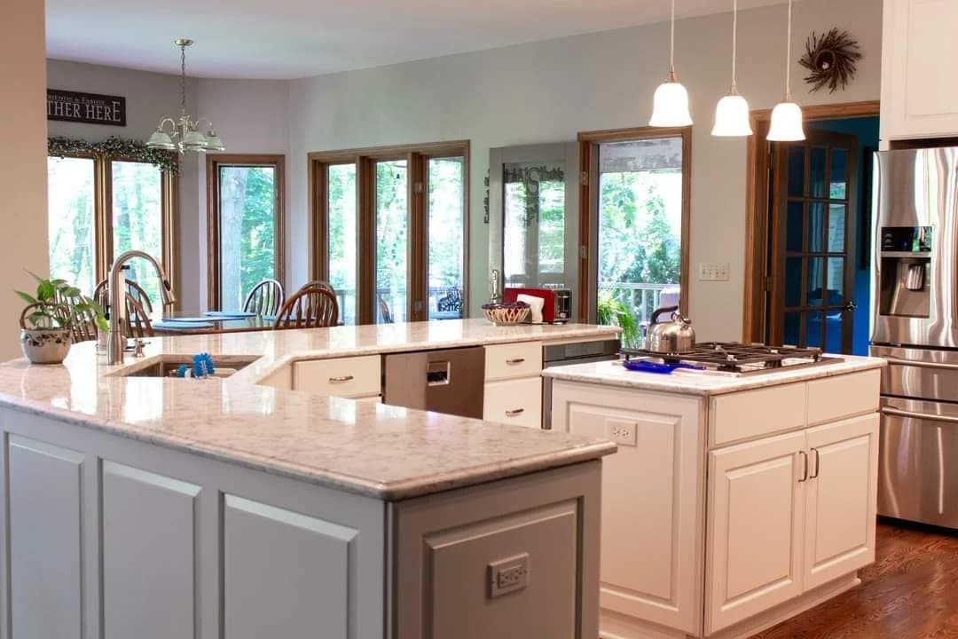 Cabinet painting by Always Perfect Painters in St. Charles, Illinois. The image shows white cabinets, a gray island, stone counters, and pendant lights.