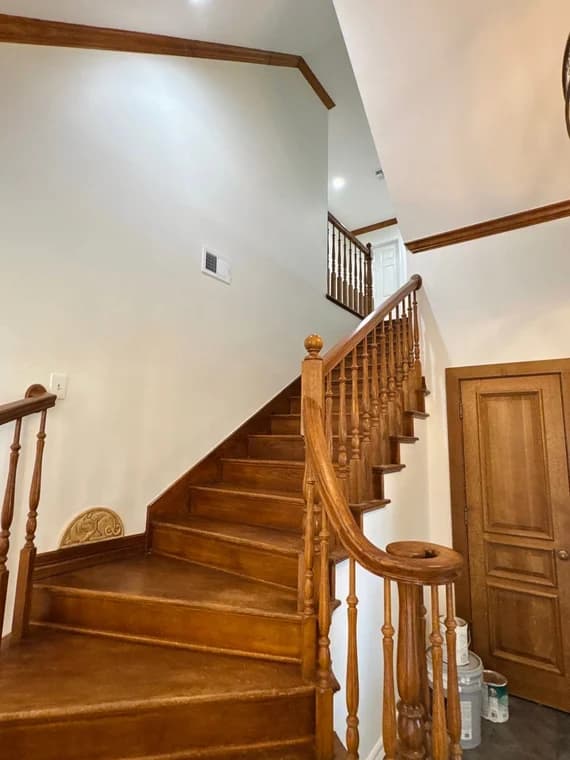 This is an image from Yellow Rose Painting, located in Texas. The staircase features natural wood steps, matching handrails, and freshly painted light walls with crown molding.