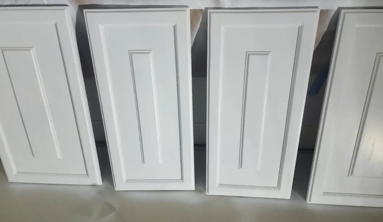 This is an image from Nkomo Painting and Contracting, located in Massachusetts. The image shows newly refinished white cabinet doors with a clean smooth finish laid out during a professional cabinet painting project.
