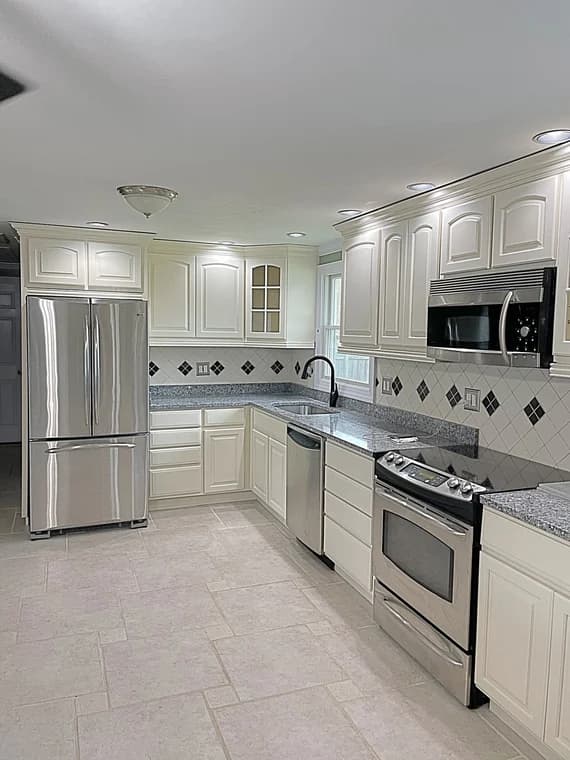 This is an image from Don Howard Painting, located in Ohio. The kitchen photo shows freshly painted cream cabinetry paired with stainless steel appliances, granite countertops, and recessed lighting.
