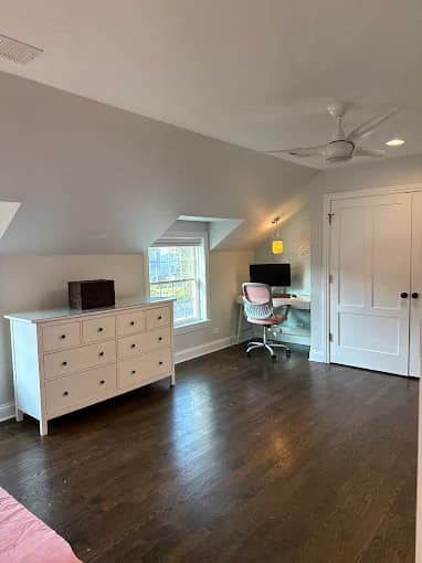 Interior painting project by Sunpainting in Northbrook, Illinois. The image shows a gray bedroom with white trim, dark wood floors, a dresser, and a desk.