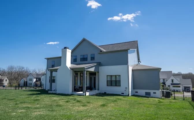 Exterior painting by AllBright Pro Painting in Smyrna, Tennessee. The image shows a white two-story home with dark window trim and a rear lawn.