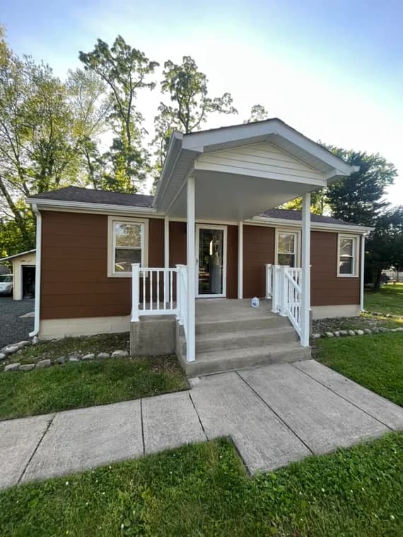 Exterior of a two-story house painted in white with black trim and shutters by Color Impact Painting Co., giving the home a refreshed, modern look.